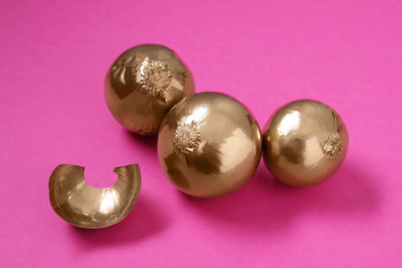 Pile of golden onions on pink background