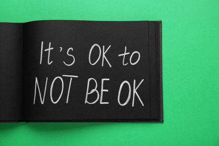 Notebook with phrase It`s Ok To Not Be Ok on green background, top viewの写真素材