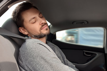 Tired handsome man sleeping in his modern car