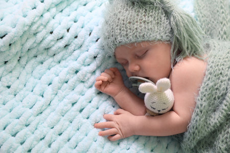 Cute newborn baby with pacifier sleeping on light blue blanket, top view. Space for text