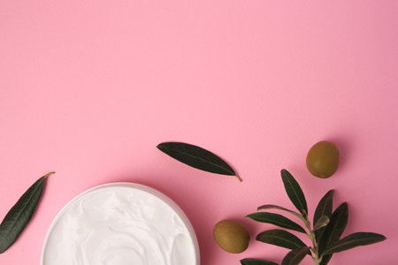 Natural cosmetic. Olive cream and ingredient on pink background, flat lay. Space for textの写真素材
