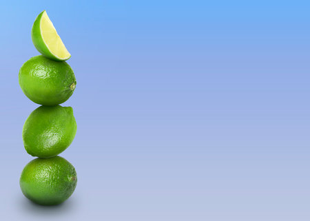 Stacked whole and cut limes on color background, space for textの写真素材