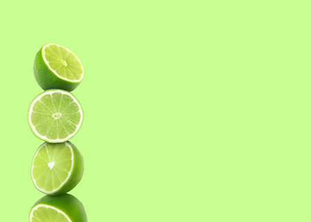 Stacked cut limes on light green background, space for text