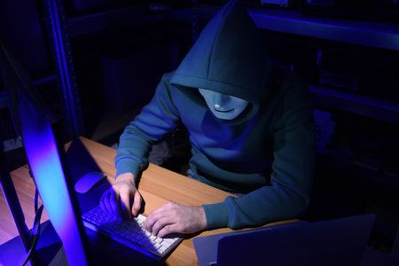 Hacker in mask working with computers in dark room. Cyber attack