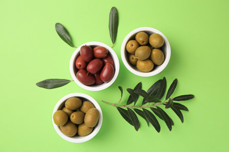 Different fresh olives and leaves on light green background, flat layの写真素材