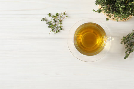 Aromatic herbal tea with thyme on white wooden table, flat lay. Space for textの写真素材