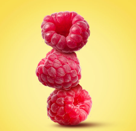 Stack of ripe raspberries on yellow backgroundの写真素材