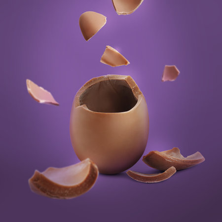 Exploded milk chocolate egg on purple backgroundの写真素材