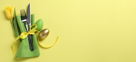 Set of cutlery, Easter eggs and tulip on yellow table, top view. Banner design with space for text
