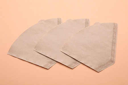 Paper coffee filters and beans on beige background, flat lay