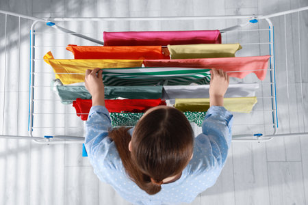 Woman hanging different apparel on clothes airer, top view
