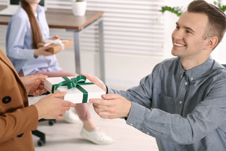 Woman presenting gift to her colleague in officeの写真素材
