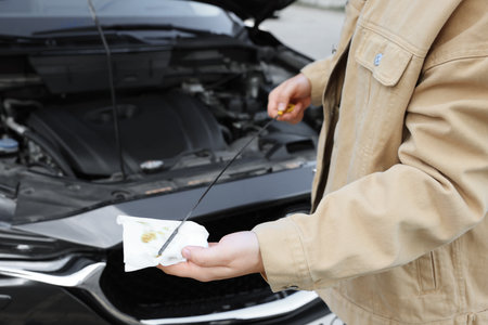 Man checking motor oil level in car with dipstick, closeup