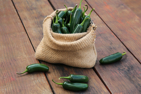 Sack with jalapeno peppers on wooden table