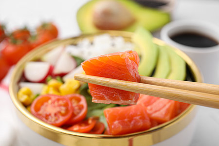 Chopsticks with salmon over delicious poke bowl, closeupの写真素材