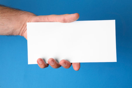Man holding flyer on blue background, closeup. Mockup for designの写真素材