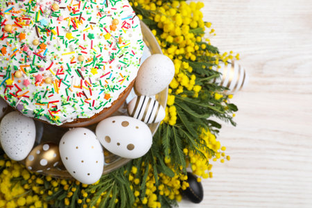 Traditional Easter cake with sprinkles, painted eggs and beautiful spring flowers on white wooden...