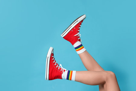 Woman in stylish gumshoes on light blue background, closeup. Space for textの写真素材