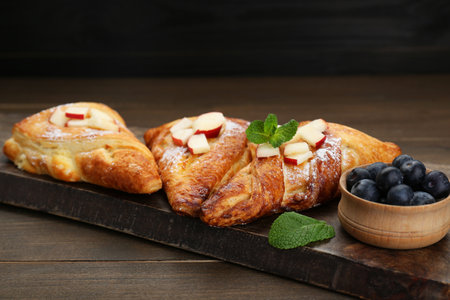 Fresh tasty puff pastry with blueberries, apples and mint served on wooden tableの写真素材