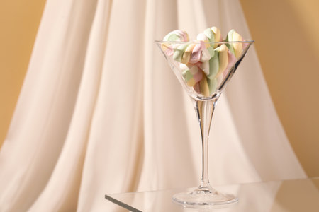 Martini glass with many tasty colorful marshmallows on table near white cloth. Space for textの写真素材