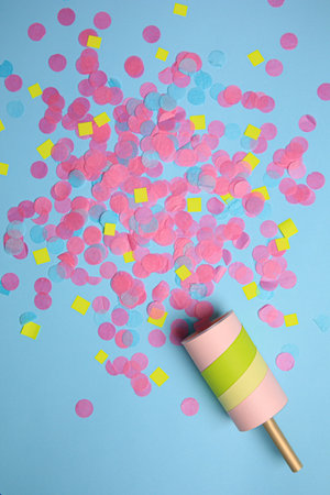 Party popper with bright confetti on light blue background, flat layの写真素材