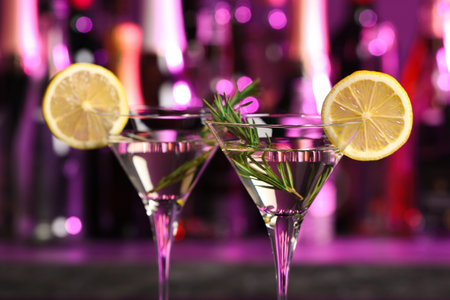 Martini glasses of refreshing cocktail, lemon slices and rosemary on blurred backgroundの写真素材