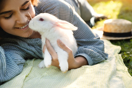 Happy woman with cute rabbit on green grass outdoors, closeupの写真素材