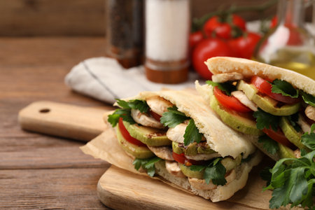 Delicious pita sandwich with grilled vegetables and parsley on wooden table, closeup. Space for textの写真素材