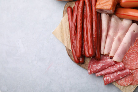 Different types of sausages on light gray table, flat lay. Space for text
