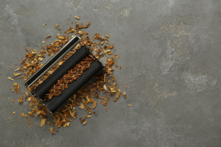 Roller with tobacco on dark gray table, top view and space for text. Making hand rolled cigaretteの写真素材