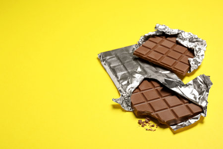 Delicious chocolate bars on yellow background, space for textの写真素材