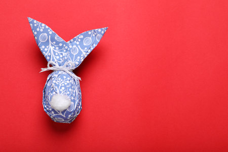 Easter bunny made of wrapping paper on red background, top view. Space for textの写真素材