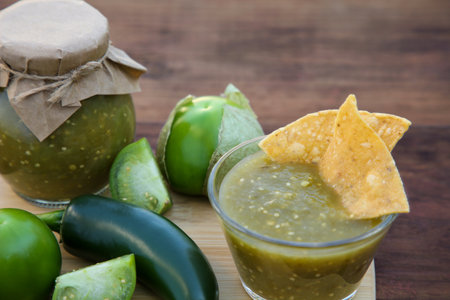 Delicious salsa sauce with tortilla chips and ingredients on wooden table, closeupの写真素材