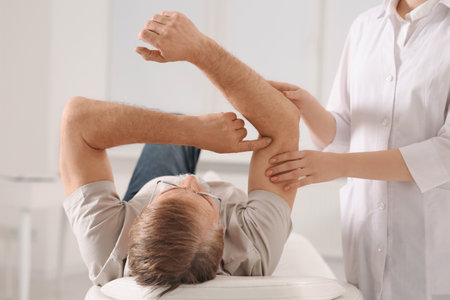 Professional orthopedist examining patient's arm in clinicの写真素材