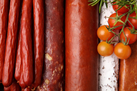 Different types of tasty sausages and tomatoes as background, top viewの写真素材