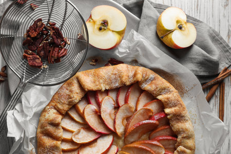 Delicious apple galette, cinnamon and pecans on table, flat layの写真素材