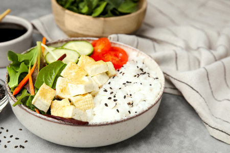 Delicious poke bowl with vegetables, tofu and mesclun on light gray tableの写真素材