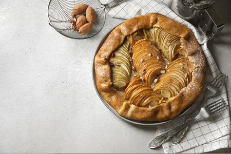 Delicious apple galette with pecans and forks on light gray textured table, flat lay. Space for textの写真素材