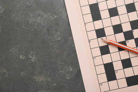 Blank crossword and pencil on gray table, top view. Space for textの写真素材