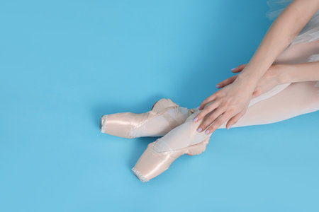 Young ballerina in pointe shoes on light blue background, top view. Space for text