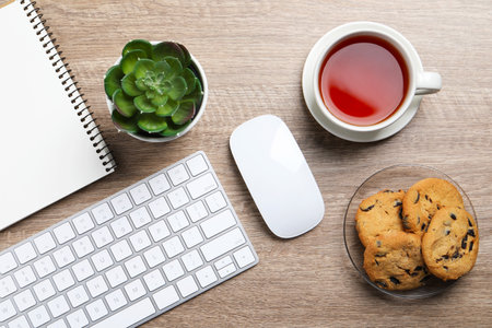 Chocolate chip cookies, tea and keyboard on wooden table at workplace, flat layの写真素材