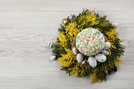 Traditional Easter cake with sprinkles, painted eggs and beautiful spring flowers on white wooden table, top view. Space for textの写真素材