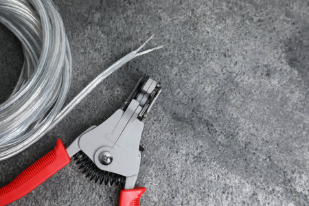 Cutters and cable with stripped wire on light gray textured table, flat lay. Space for text