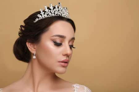 Beautiful young woman wearing luxurious tiara on beige background, space for textの写真素材