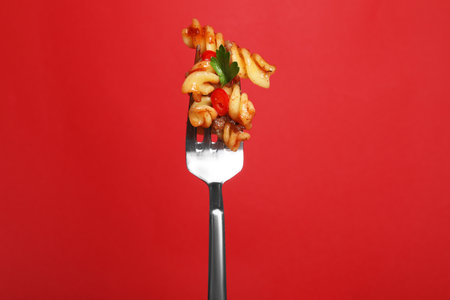 Fork with tasty pasta on red backgroundの写真素材