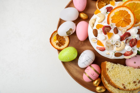 Traditional Easter cake with dried fruits and painted eggs on white table, top view. Space for text