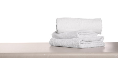 Soft terry towels on light table against white background, space for textの写真素材