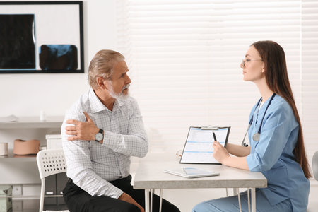 Orthopedist examining patient with injured arm in clinicの写真素材
