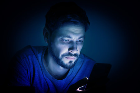 Internet addiction. Man using smartphone at night. Toned in blueの写真素材