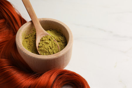 Bowl of henna powder and red strand on white marble table, closeup with space for text. Natural hair coloringの写真素材